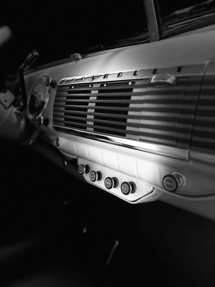 Black-and-white close-up of a vintage car dashboard with radio and control knobs.