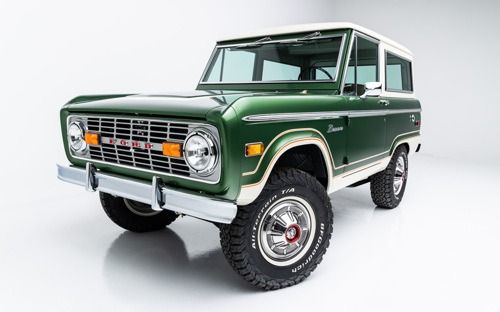 Classic green vintage Ford Bronco SUV on a white background, front three-quarter view.