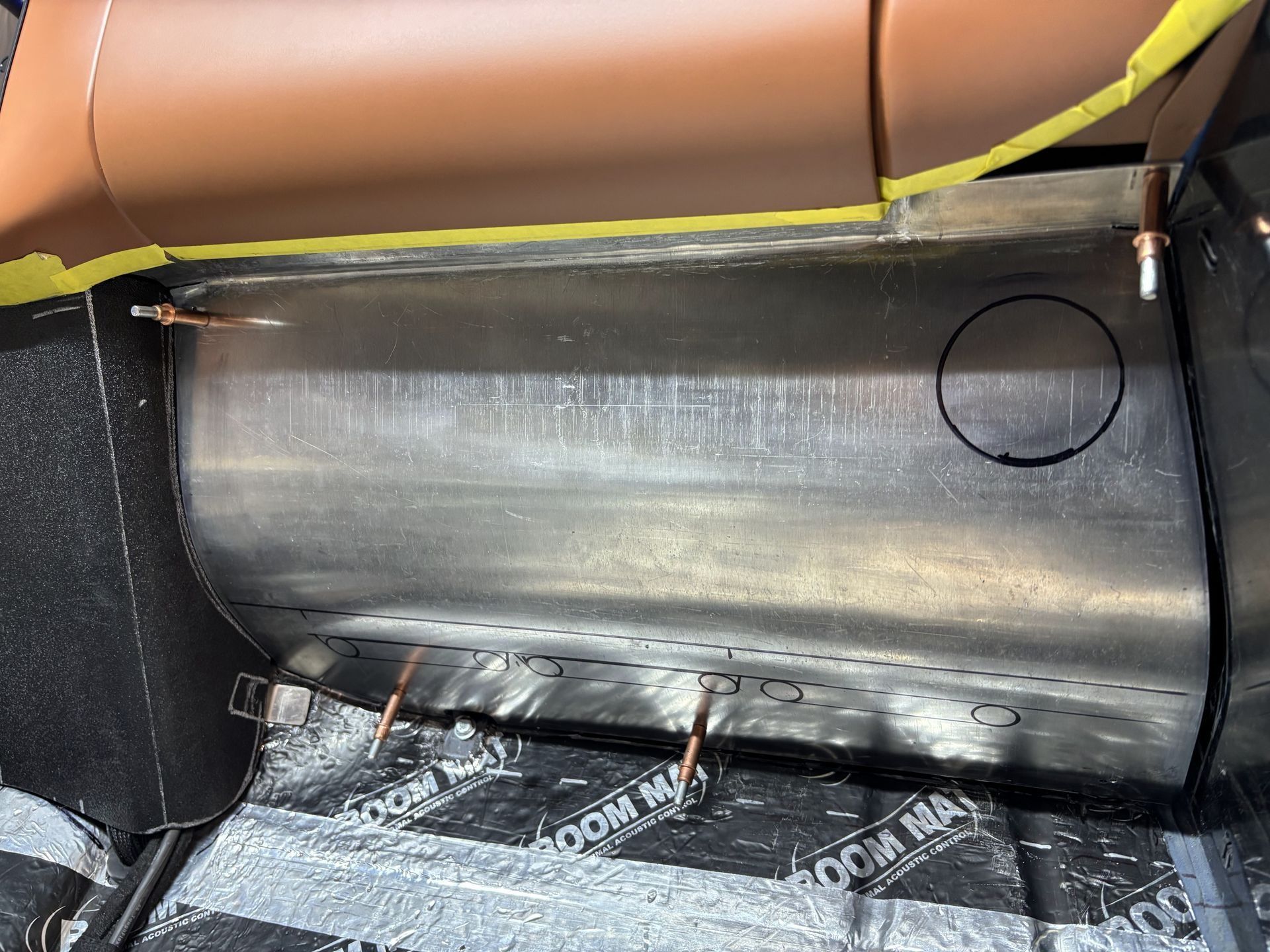 Car interior with a black plastic seat-back panel and brown upholstery above it.