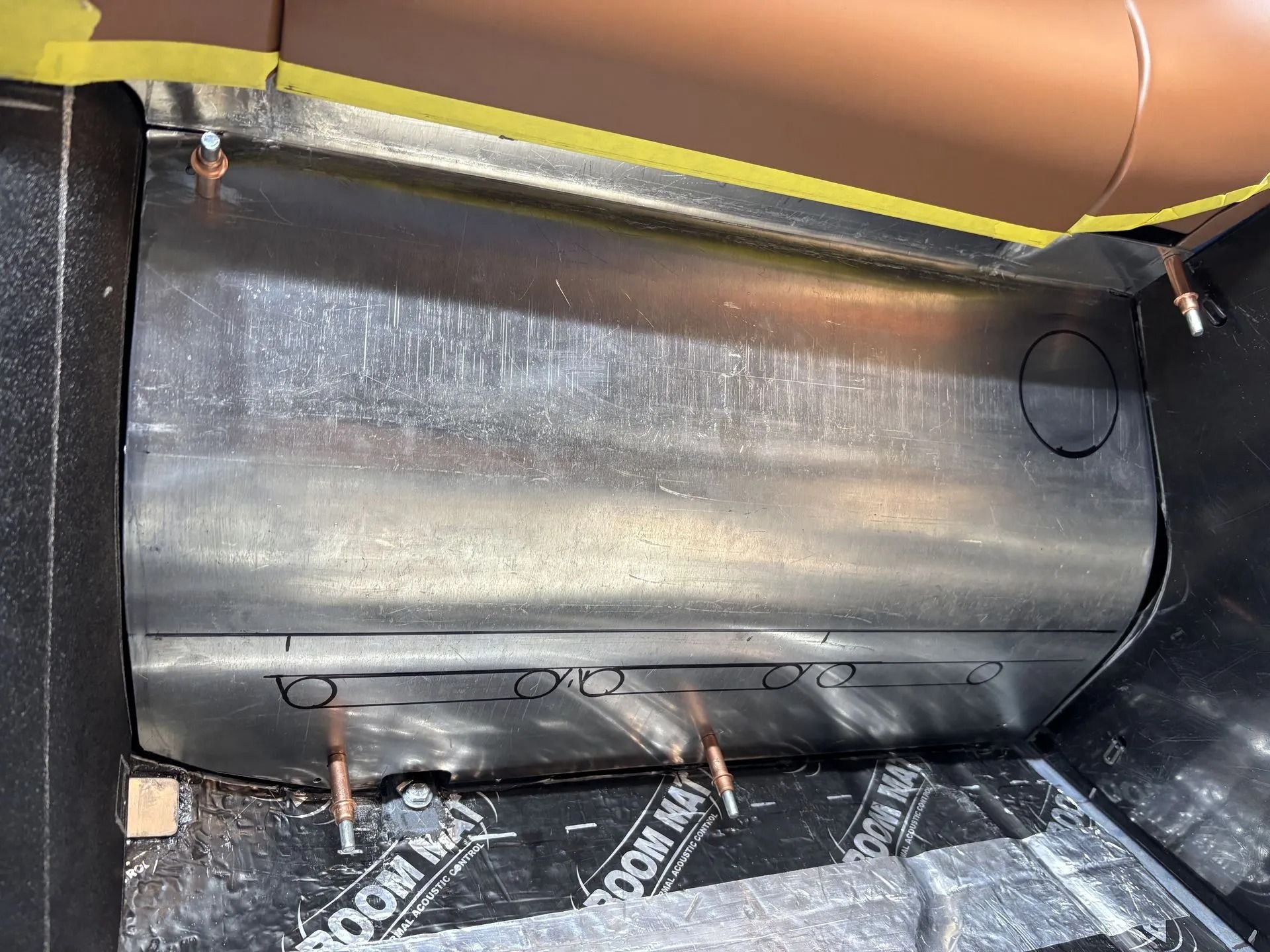 Black insulated duct or vent inside a metal compartment, with taped seams and wiring visible underneath