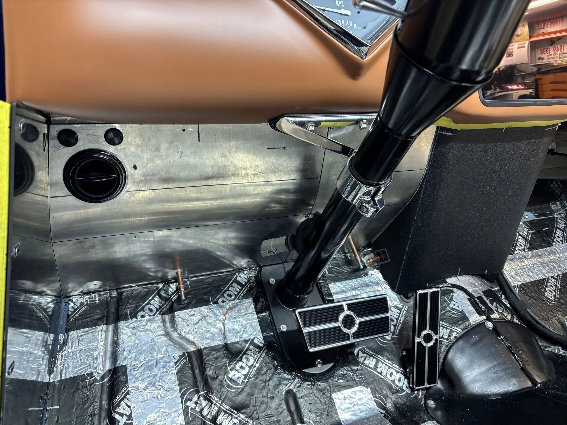 Interior of a vehicle with exposed metal floor, gear lever, and dashboard controls, showing a stripped cabin.