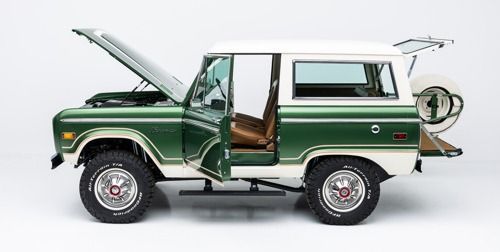 Green vintage SUV with hood open and side door open, shown in profile on a white background