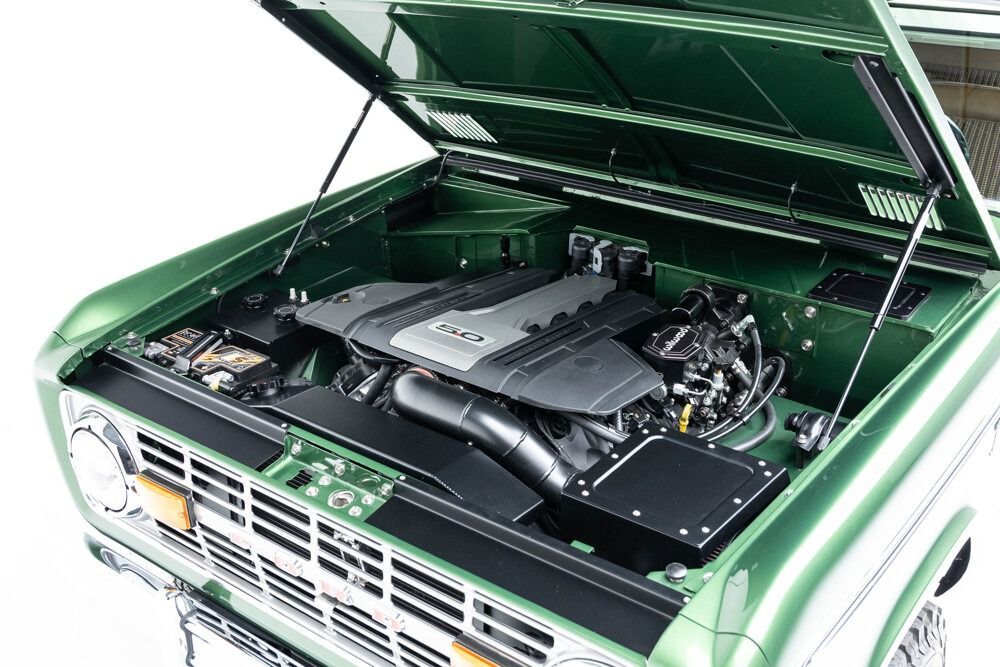 Green car engine bay with open hood, showing a modified engine compartment