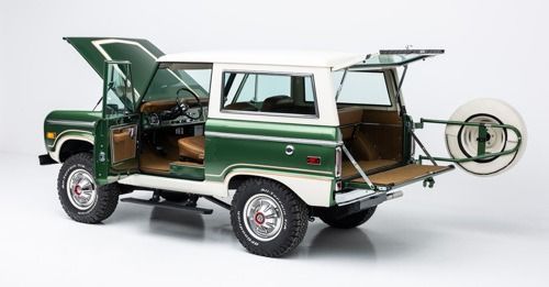 Vintage green SUV with doors and rear tailgate open, showing a tan interior and rear-mounted spare tire.