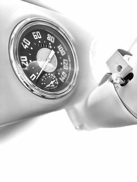 Close-up of a vintage car dashboard with a chrome speedometer and ignition key in black and white.
