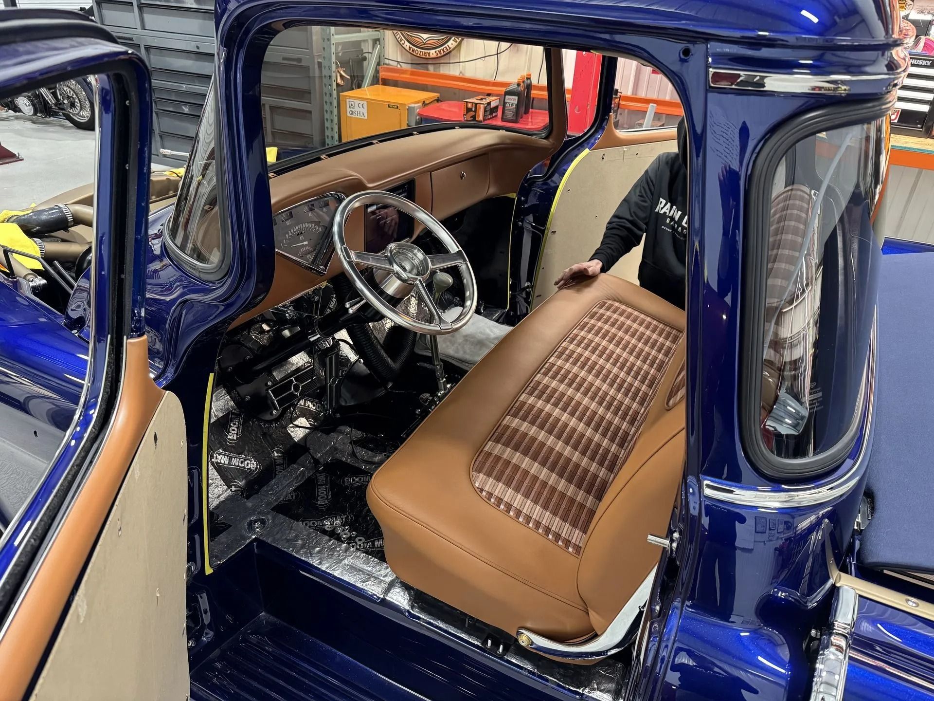 Blue classic car interior with tan seats and a chrome steering wheel, viewed through the open door