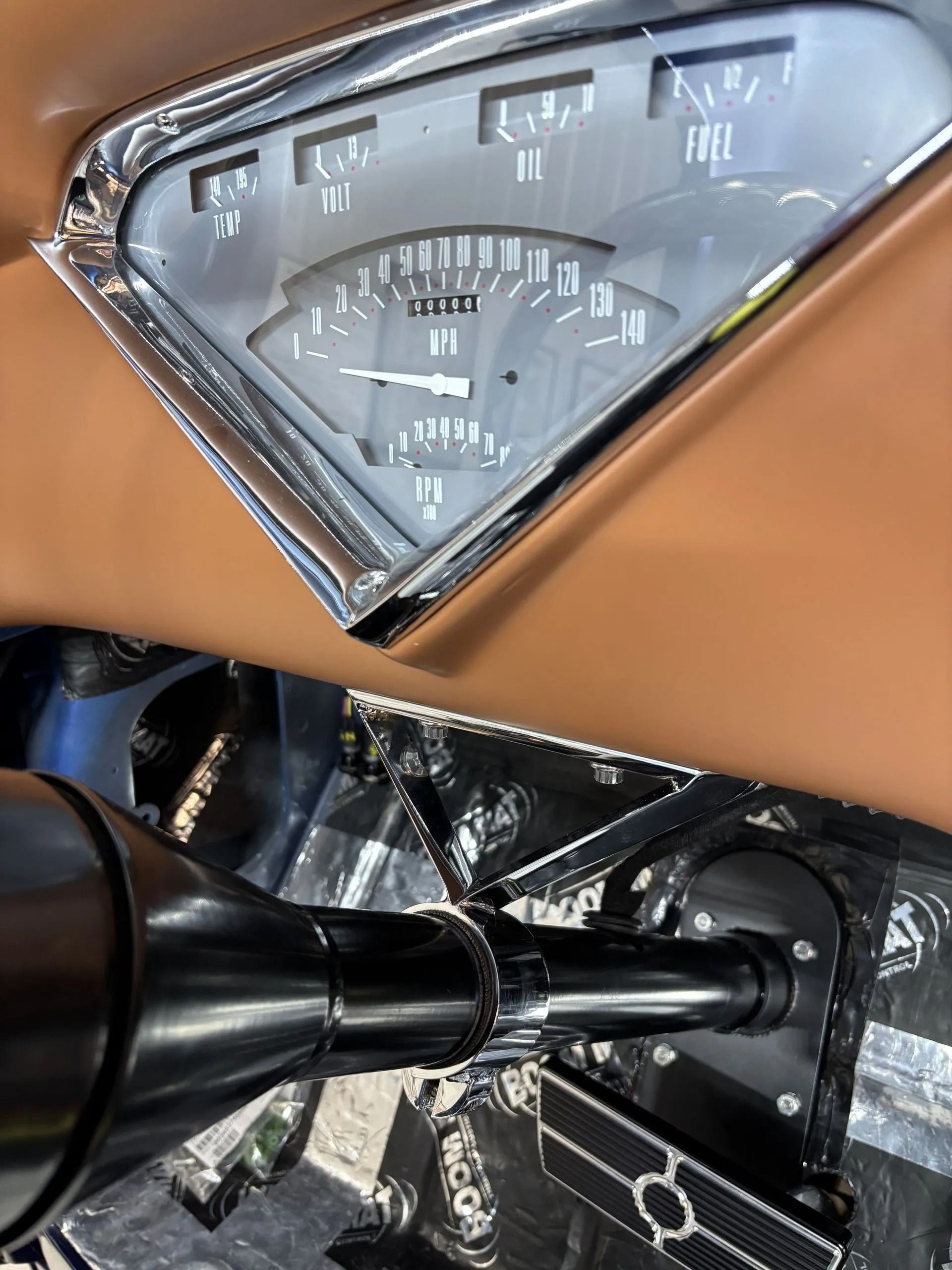 Close-up of a motorcycle dashboard and chrome handlebar under a tan fairing.