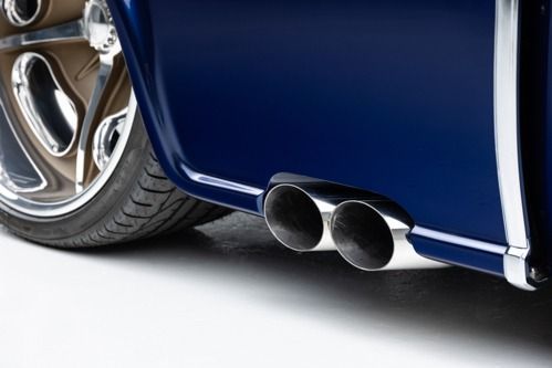 Close-up of a blue sports car’s rear wheel and dual exhaust pipes