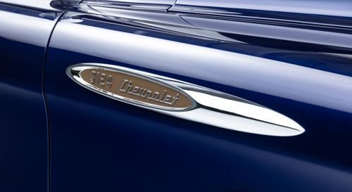 Close-up of a blue car’s chrome side vent badge with a silver accent