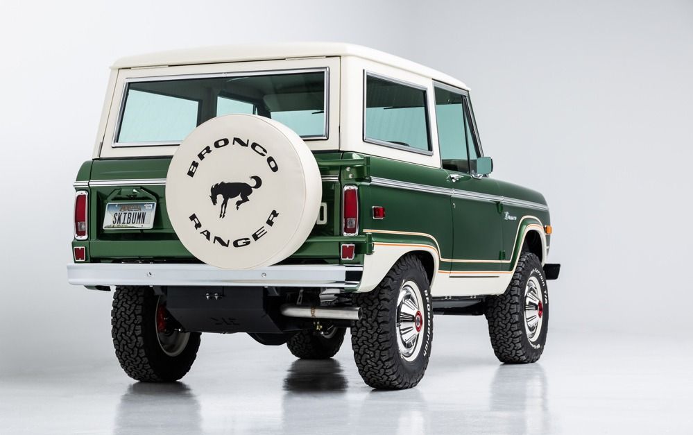 Classic green-and-white Ford Bronco SUV with a rear-mounted spare tire, shown on a white background