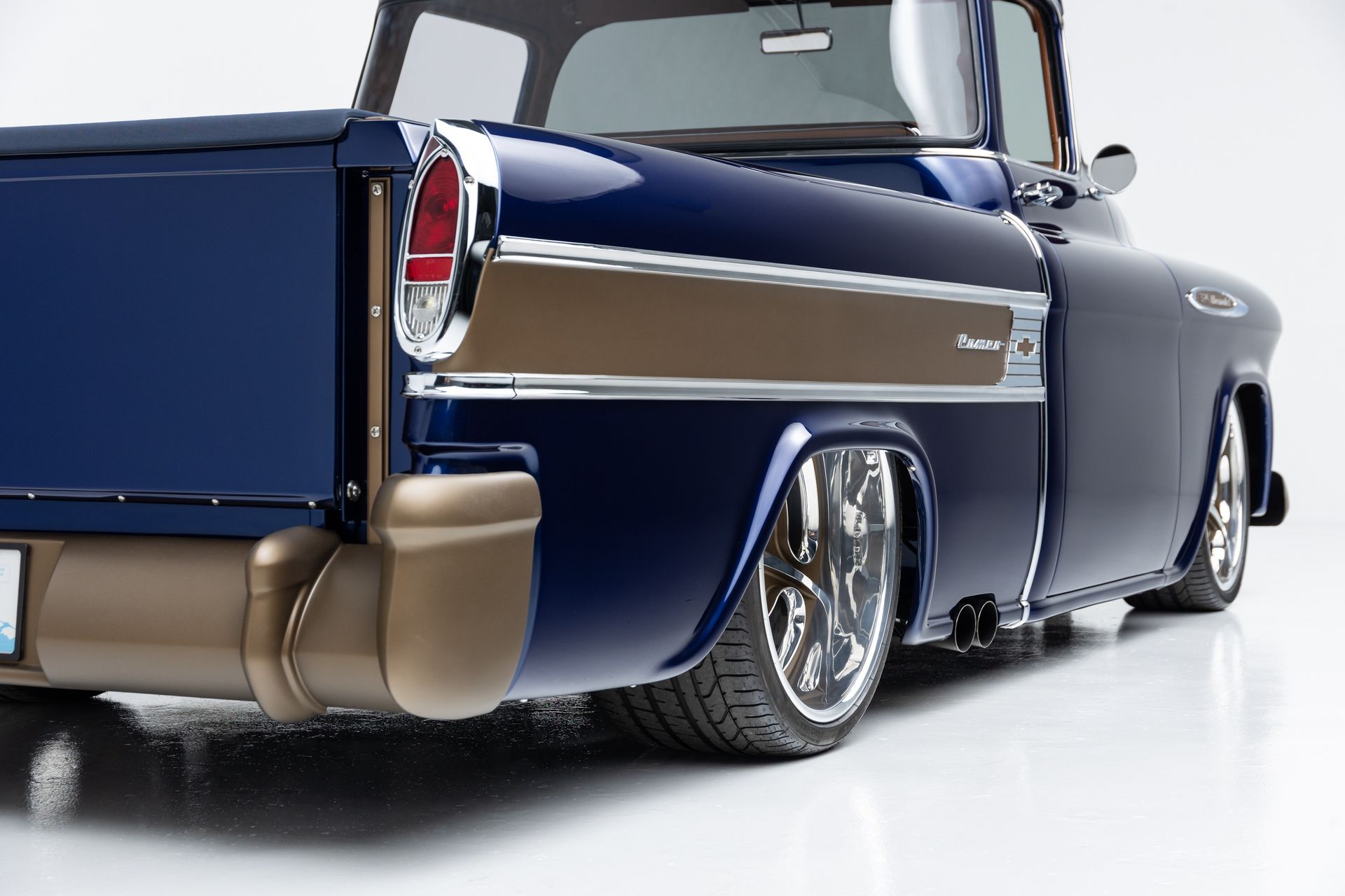 Rear view of a dark blue classic pickup truck with chrome trim on a white studio background
