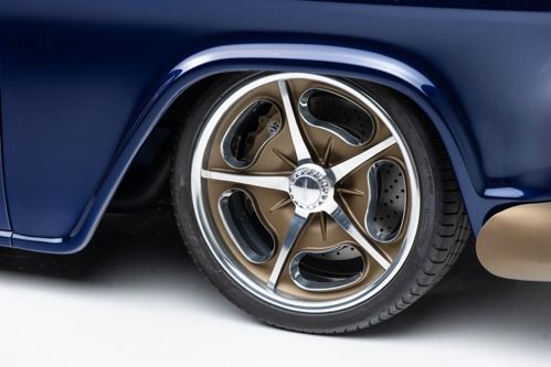 Close-up of a blue classic car’s chrome wheel and tire, showing bronze rim details.