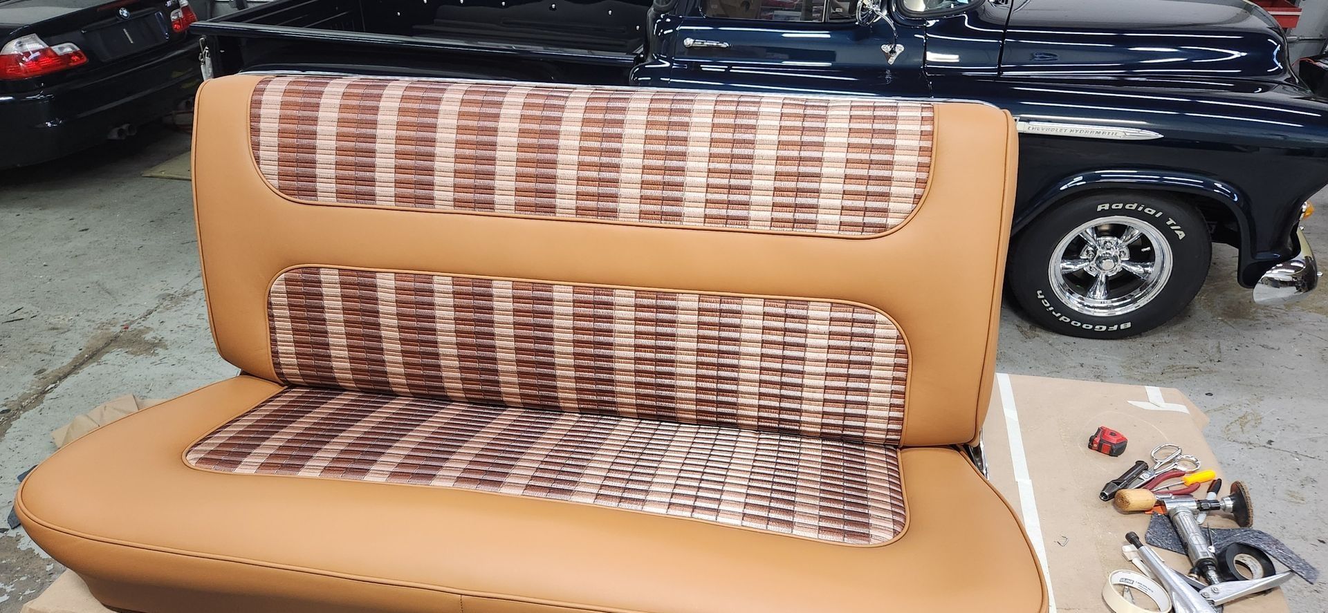 Tan and brown tufted car bench seat with woven inserts, shown in a garage or workshop.