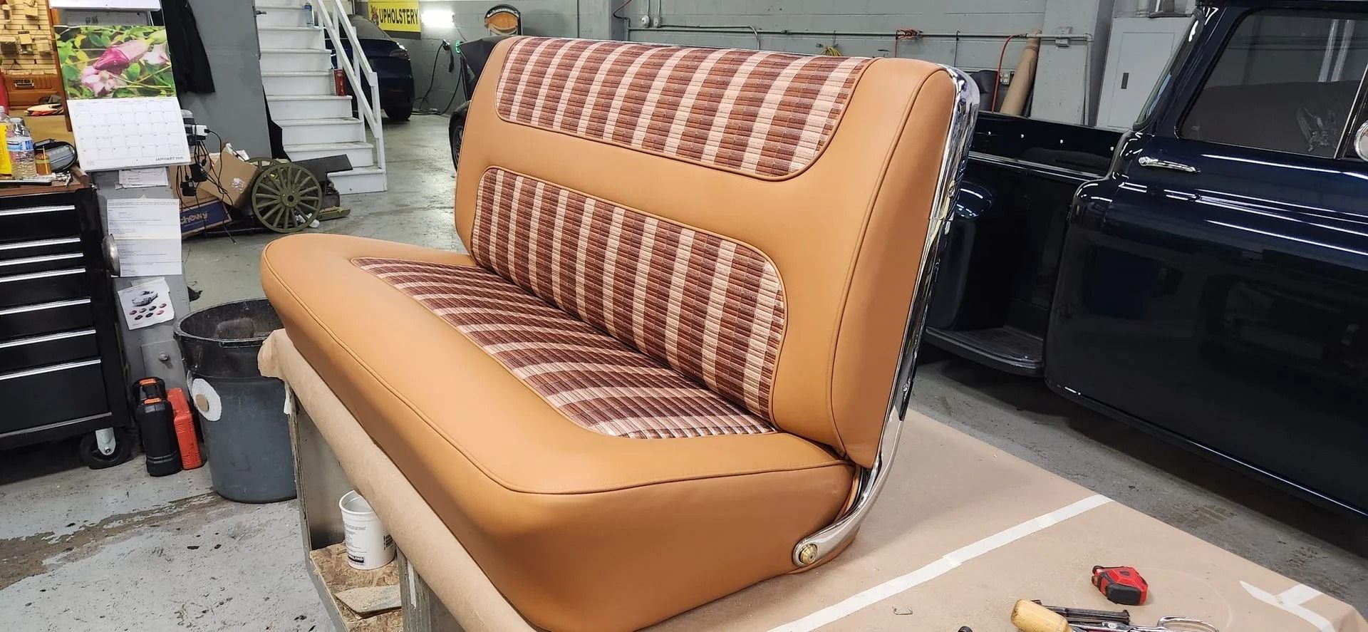 Orange sofa with patterned backrest in a workshop or furniture store, shown with a black car nearby