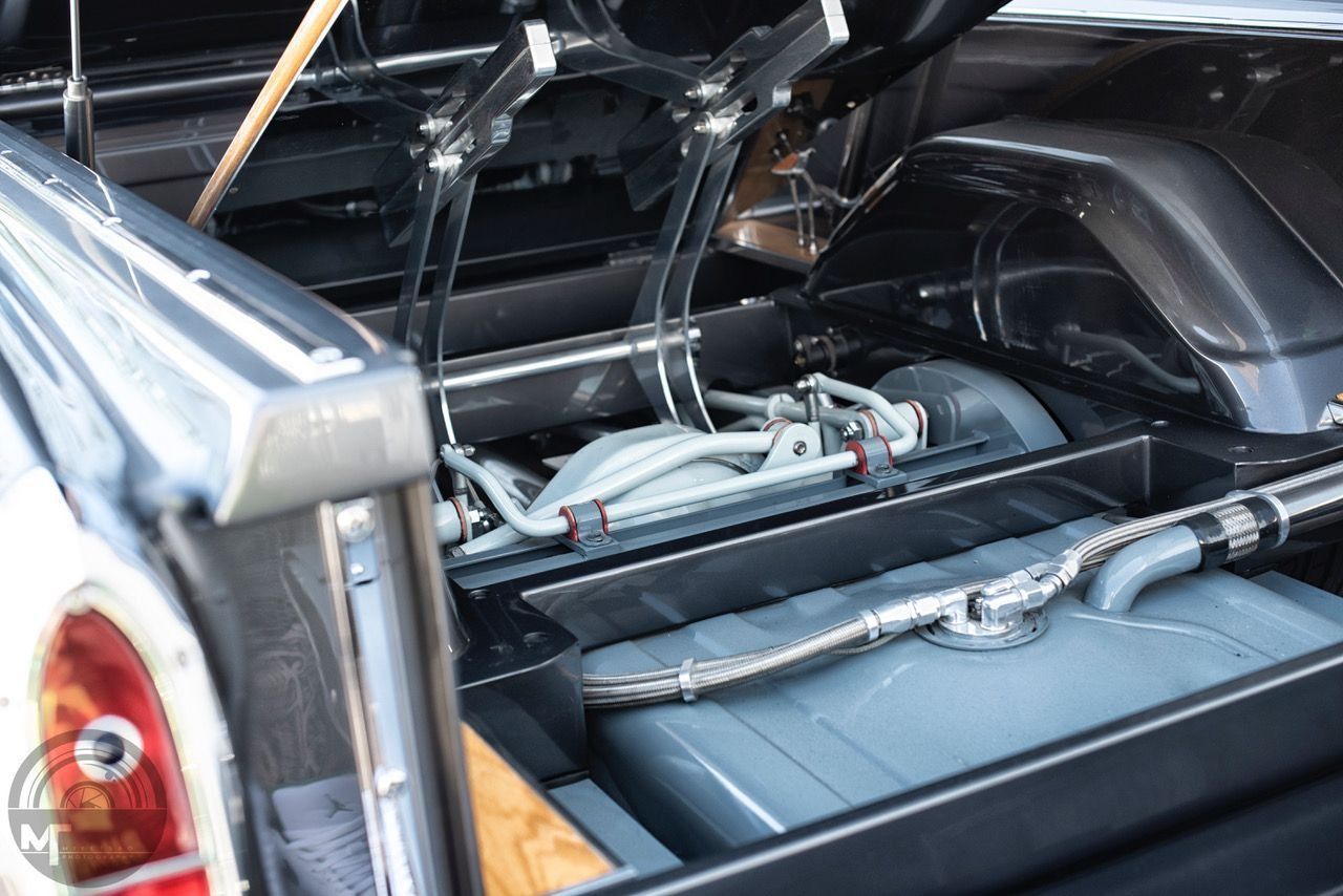 Car trunk with a large black subwoofer and audio components installed under the rear shelf.