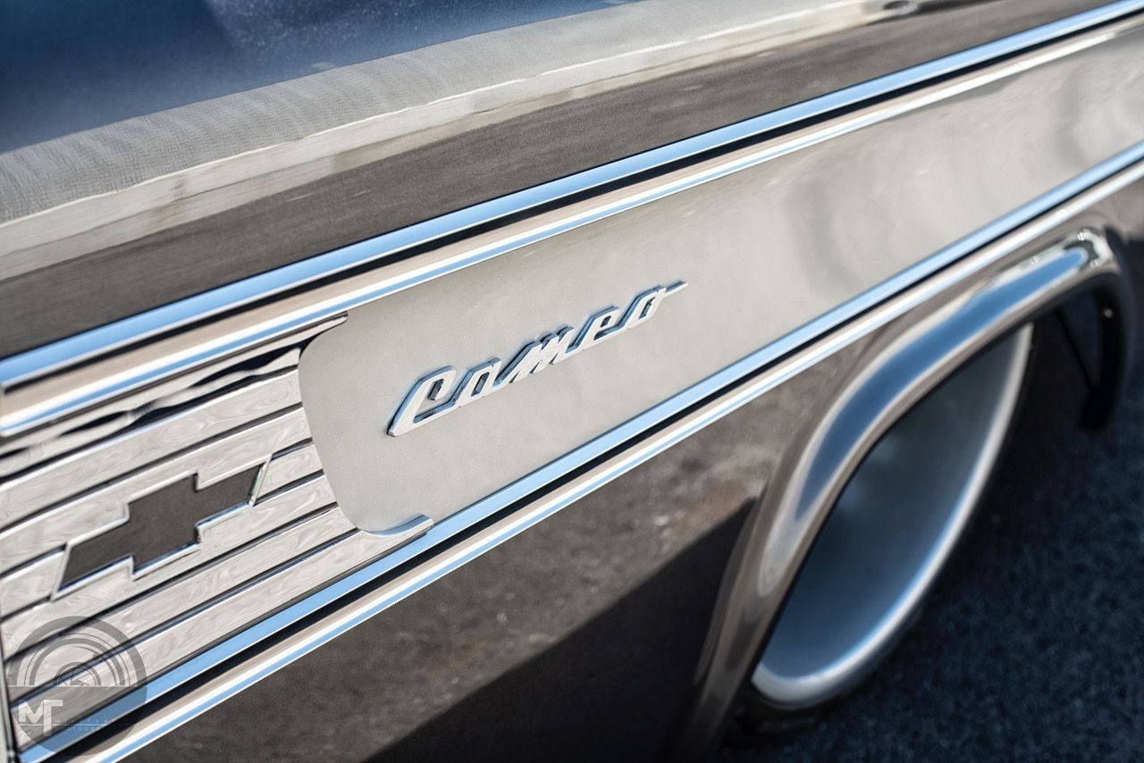 Close-up of a classic car’s chrome side trim and wheel in bright sunlight