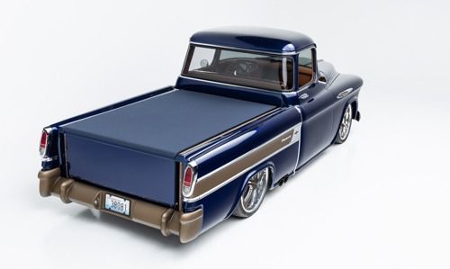 Dark blue vintage pickup truck with chrome trim, shown from the rear in a studio setting