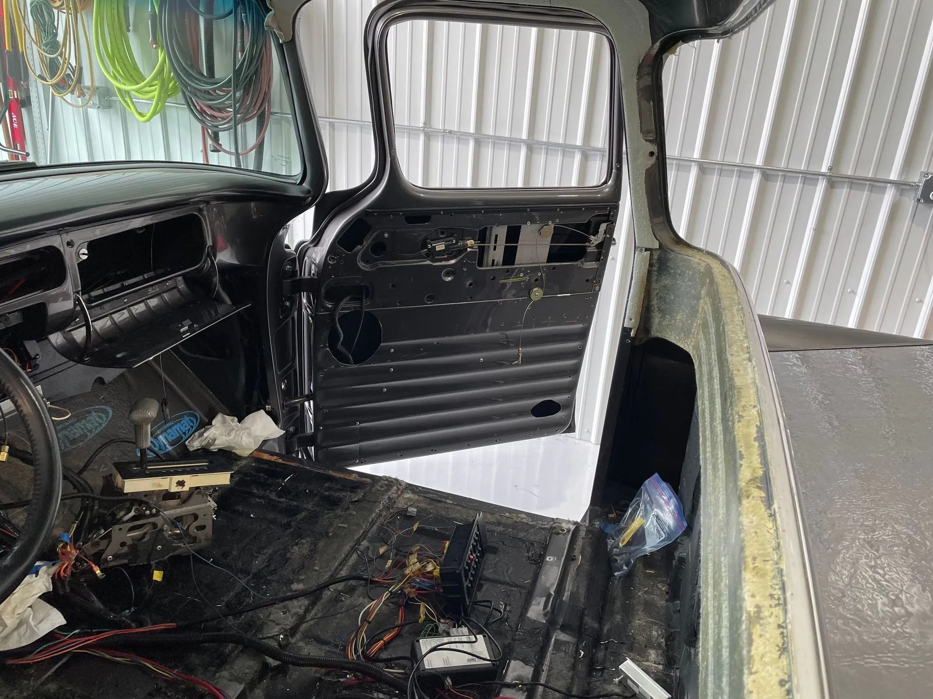 Interior of a stripped old car with exposed metal and wiring inside a garage