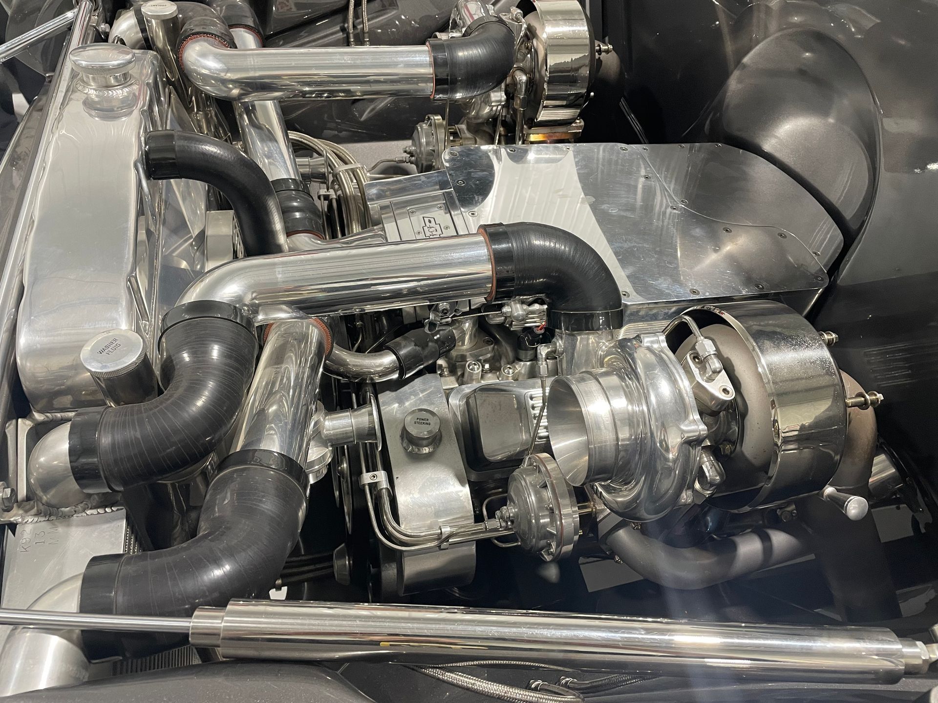 Polished turbocharger and metal piping assembly inside an engine bay or industrial machinery compartment