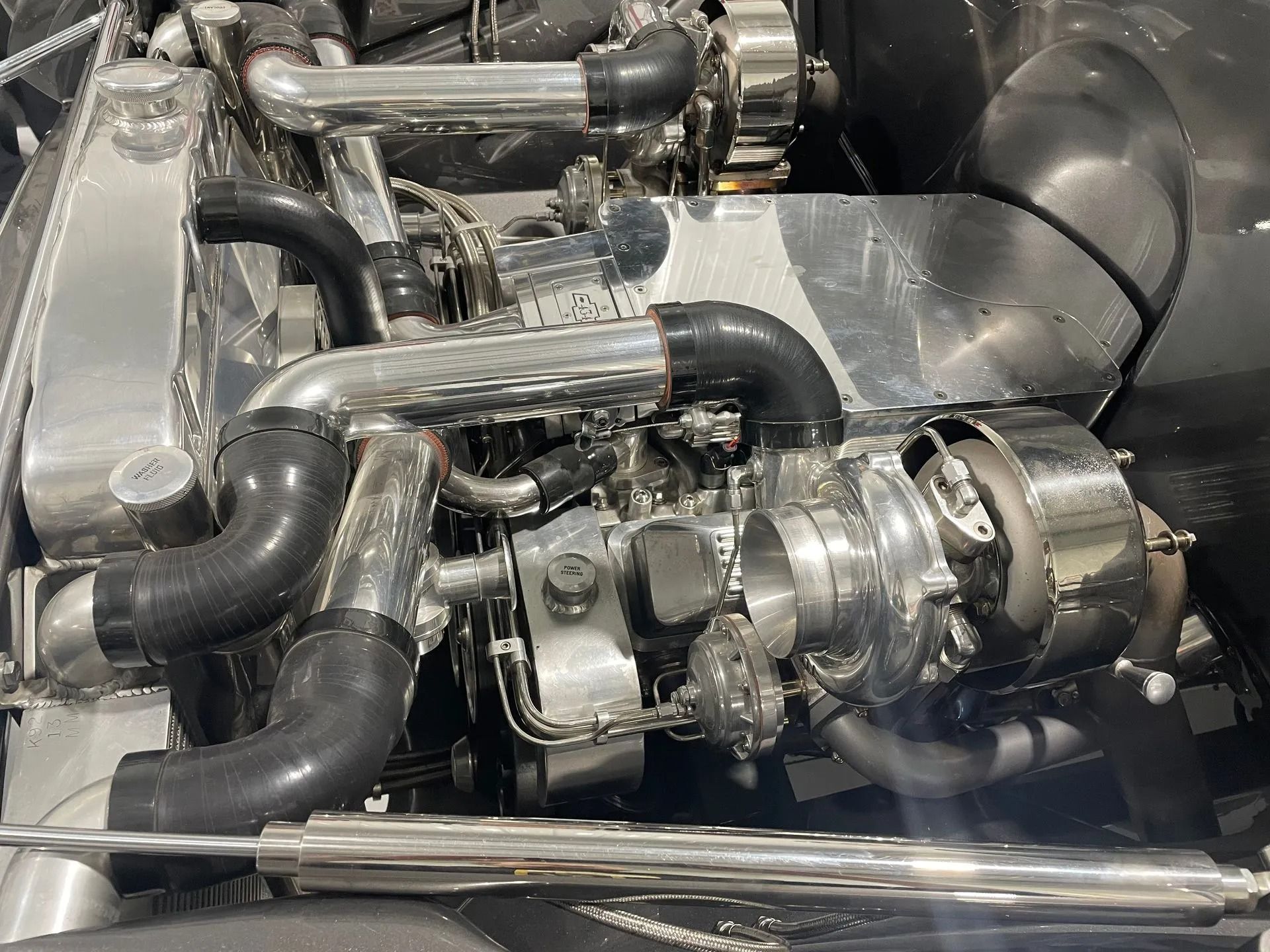 Close-up of polished metal turbocharger and exhaust piping inside an engine bay.