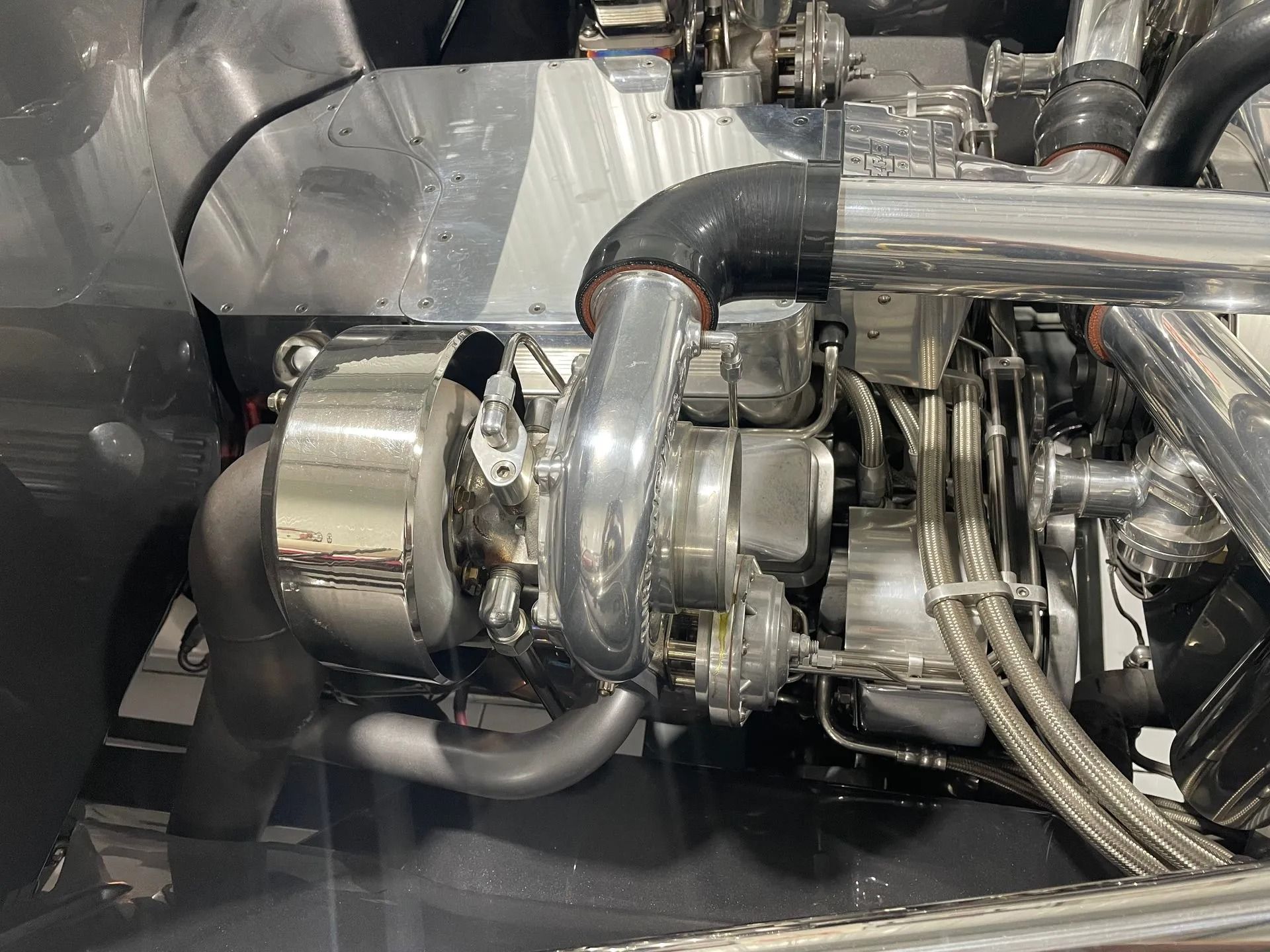 Shiny industrial engine turbocharger with metal pipes and braided hoses inside a machine compartment