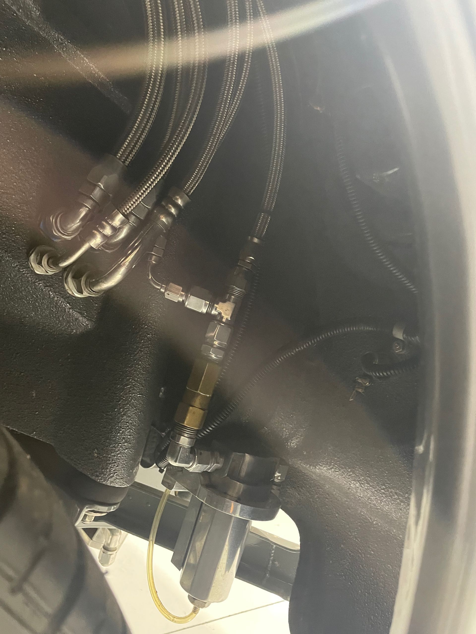 Close-up of a black mechanical component with metal fittings and cables inside a machine or vehicle.