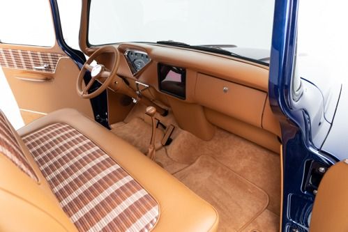 Vintage car interior with tan upholstery, plaid bench seat, and blue door frame