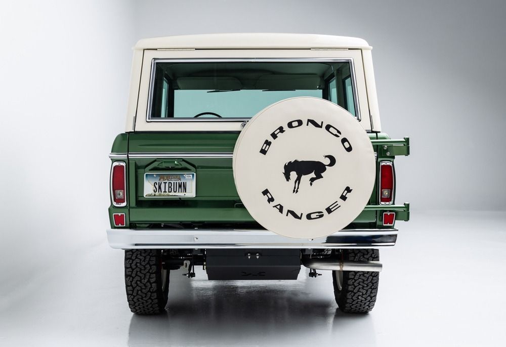 Rear view of a green and white vintage SUV with a spare tire mounted on the back