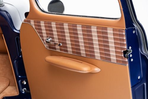 Two-tone car door interior with tan leather and striped wood paneling, open against a blue exterior.