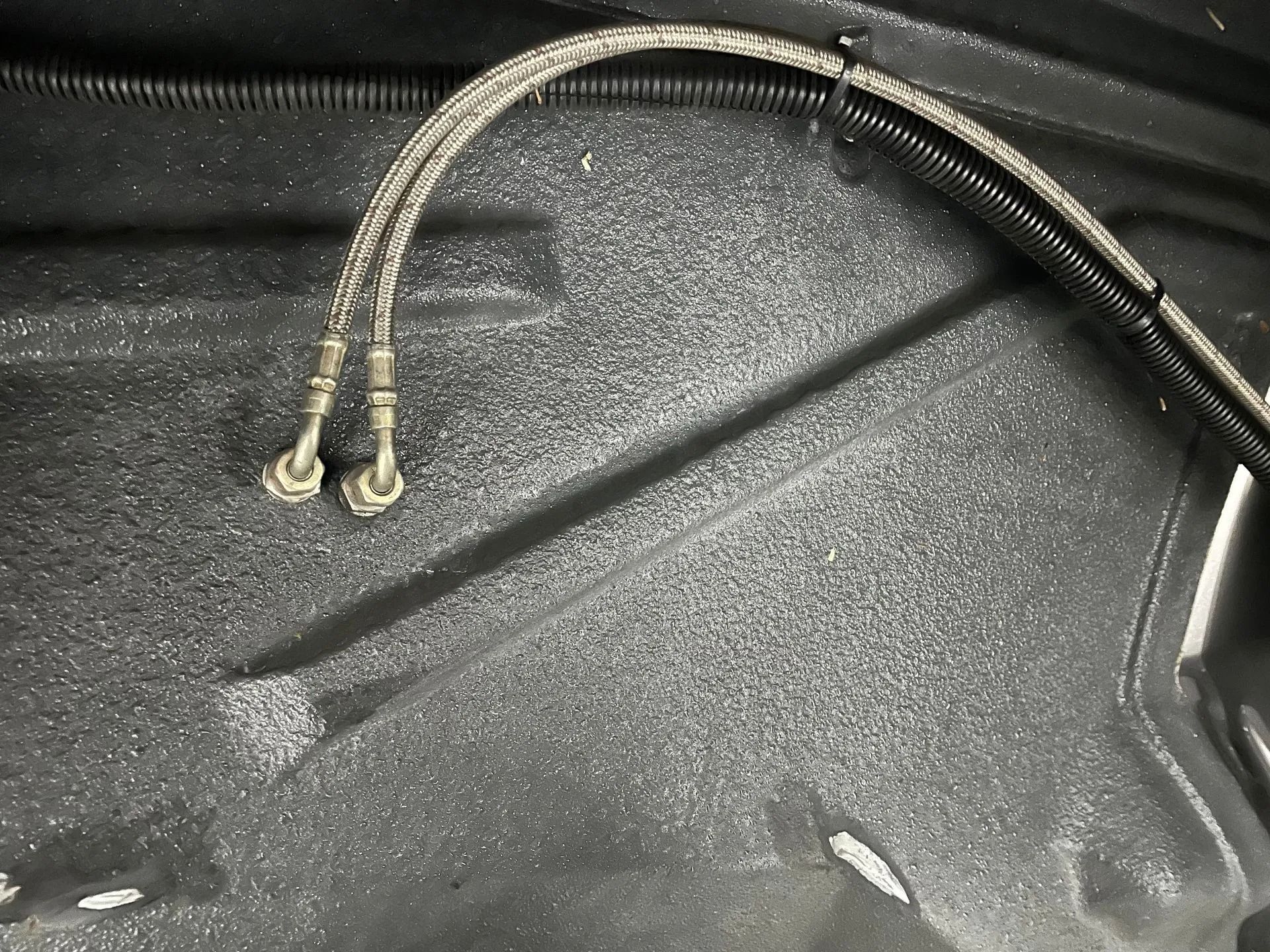 Two black braided cables with metal clips on a textured black surface