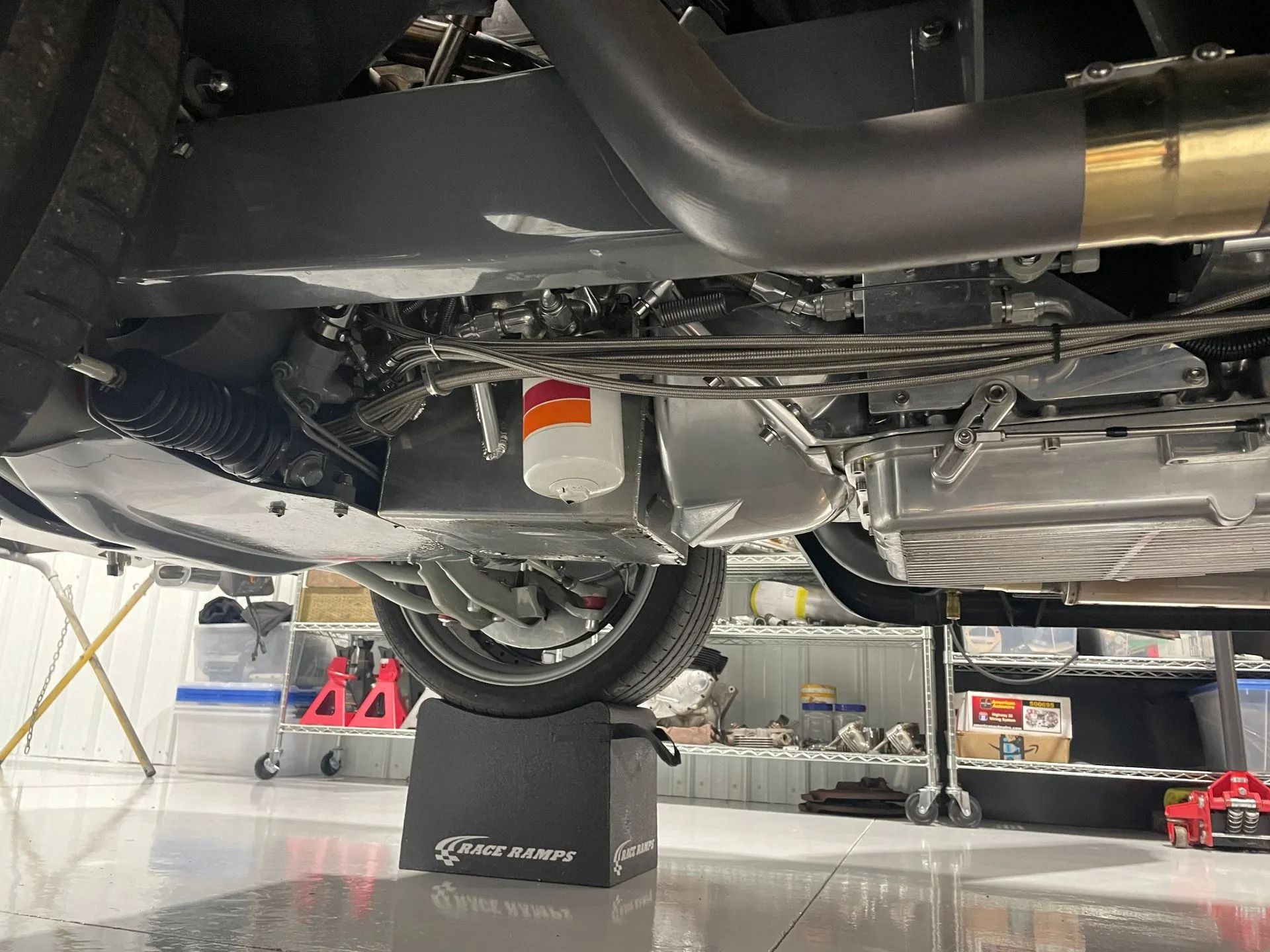 Undercarriage of a car on a lift in a garage, with exhaust and suspension visible.
