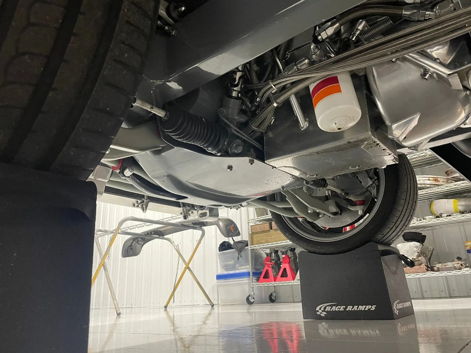 Undercarriage of a sports car on a lift in a garage, showing suspension and exhaust components
