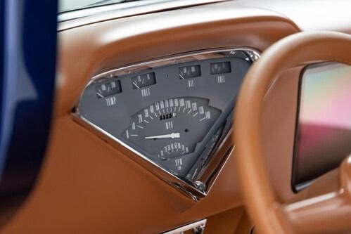 Close-up of a vintage car dashboard gauge cluster with tan leather trim and chrome accents
