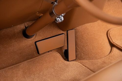 Car interior close-up of a tan seat and seatbelt buckle beside the center console.