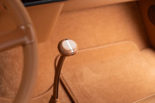 Close-up of a brown leather car interior with a silver-topped gear shift lever