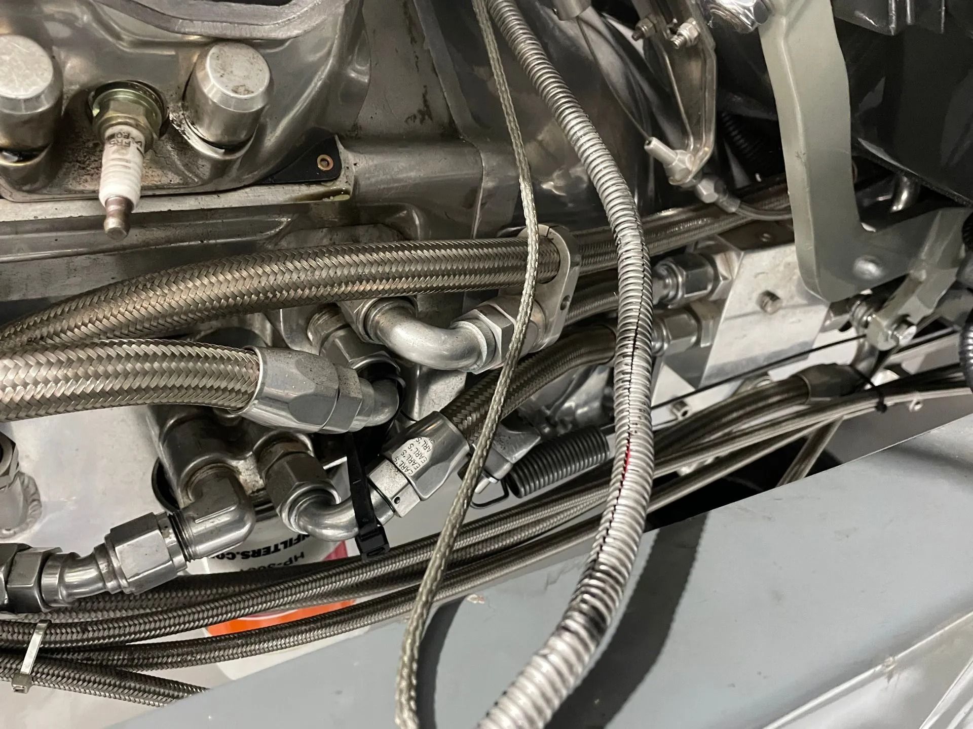 Close-up of metal tubing, braided hoses, and engine components in a mechanical assembly