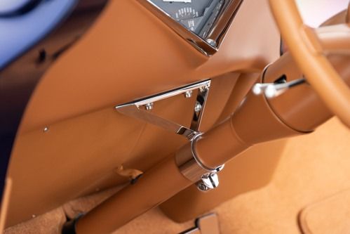Close-up of orange metal tubing and chrome triangular brackets on a vehicle frame