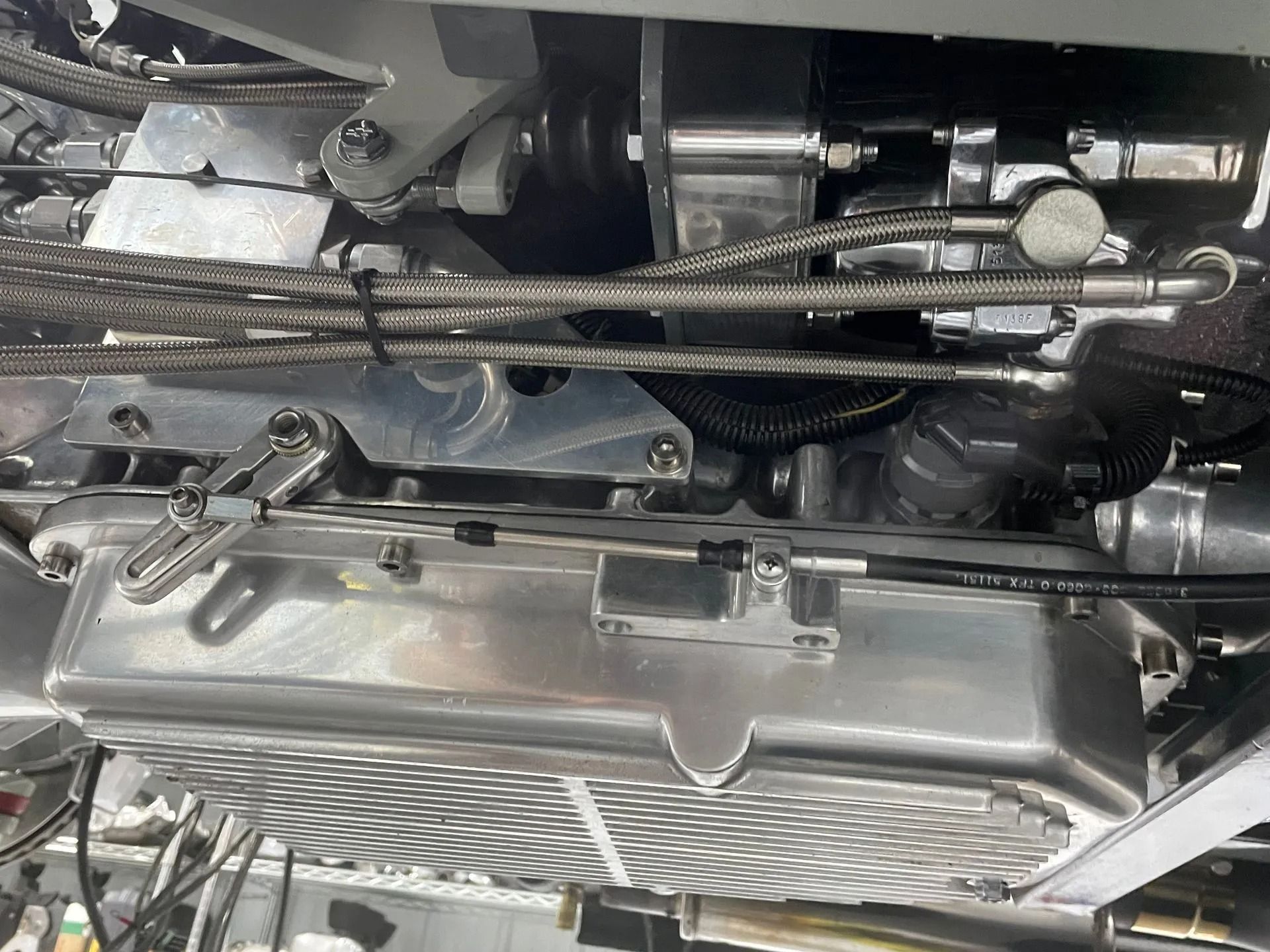 Close-up of a car engine bay with hoses, metal components, and a radiator fan visible
