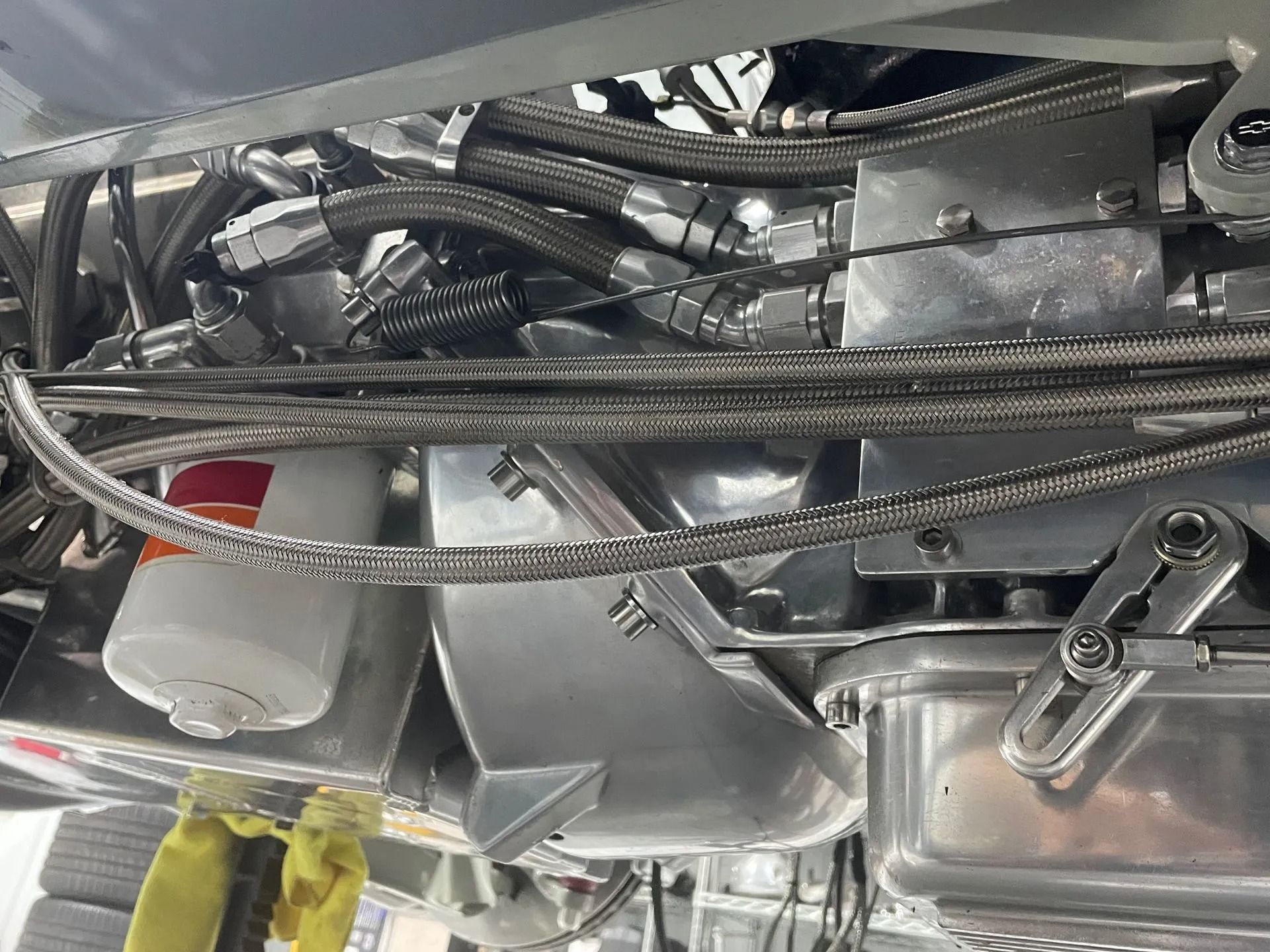 Close-up of motorcycle engine components with wiring, metal parts, and a red-topped canister under the frame
