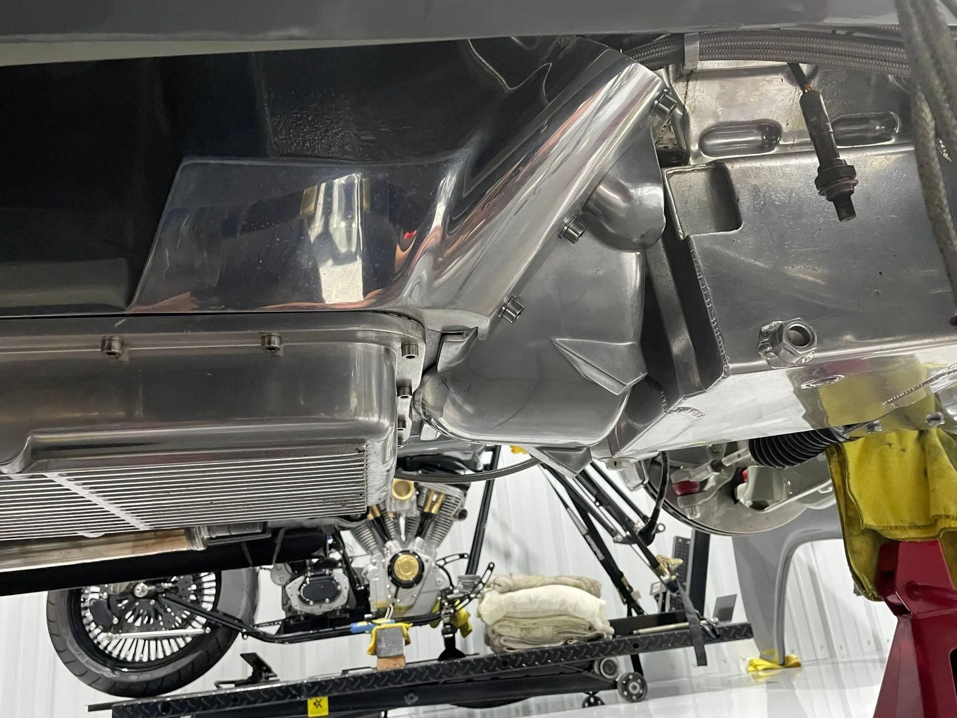 Shiny metal car undercarriage with exhaust and suspension components visible in a garage