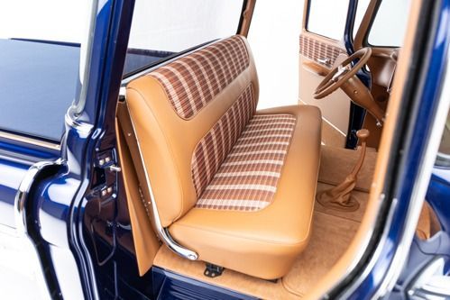 Vintage car interior with tan and brown checkered bench seats and blue door frame