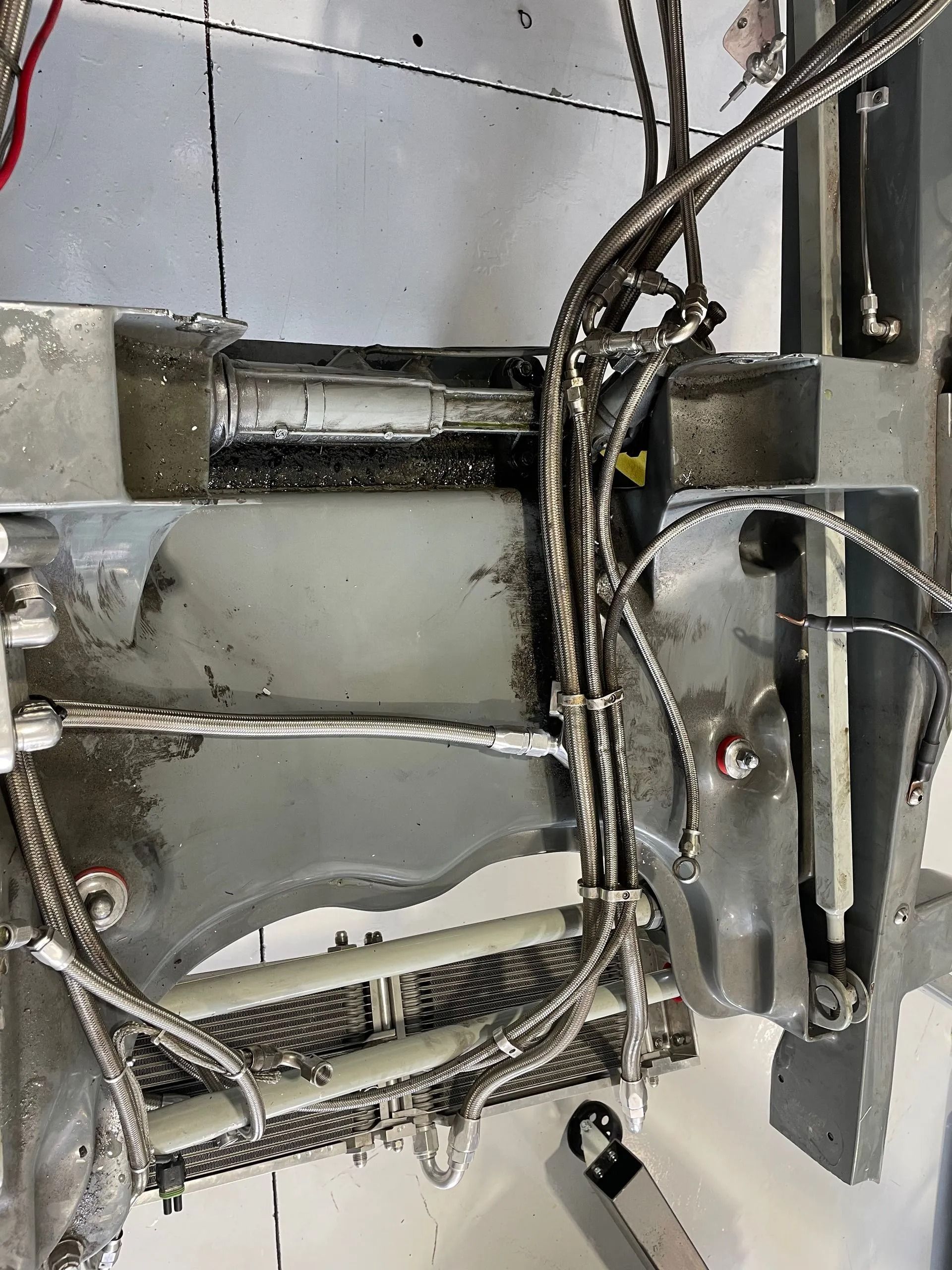 Close-up of tangled electrical wires and metal brackets inside a gray machine panel