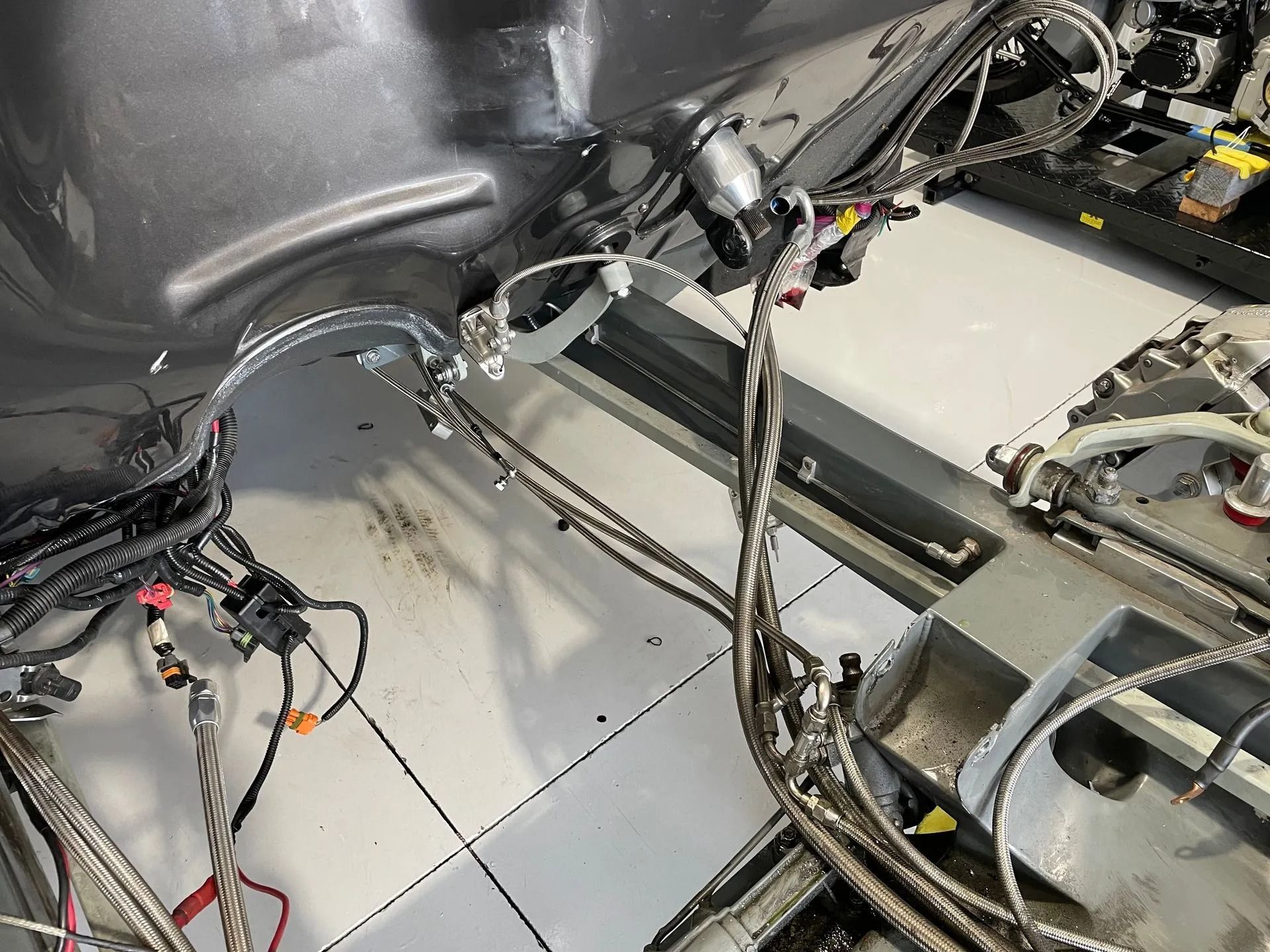 Interior of a vehicle with exposed wiring harnesses and metal floor panels during assembly or repair