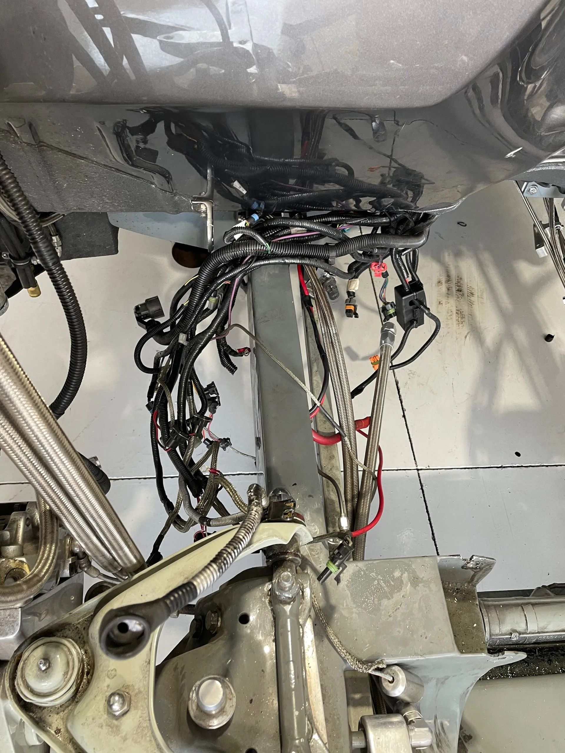 Wiring harness and mechanical linkage inside a vehicle’s underside, with exposed cables and metal components.