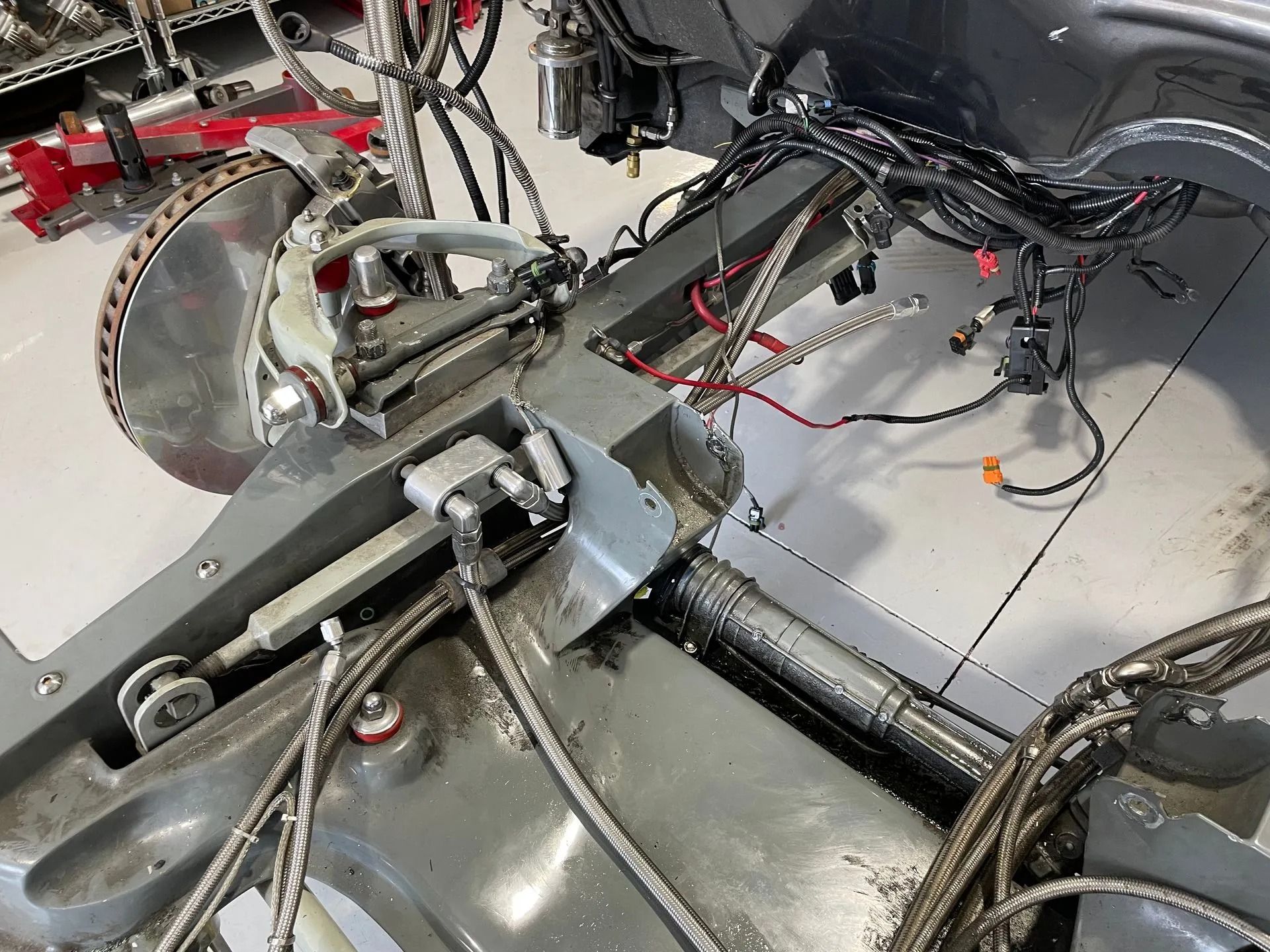 Close-up of a mechanical assembly with metal arms, cables, and a circular saw blade on a workshop floor