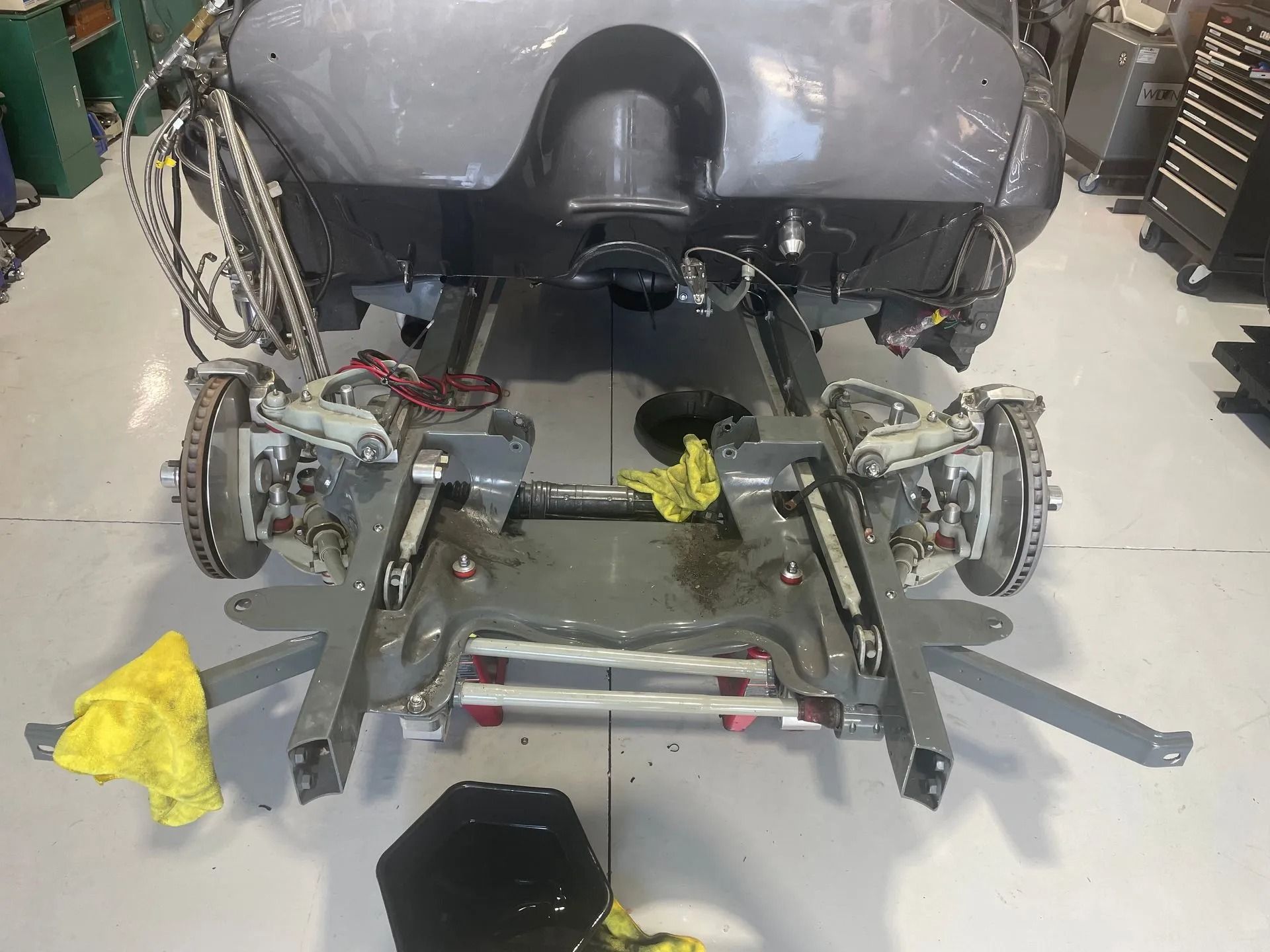 Car on a garage lift with exposed suspension and tools on the floor