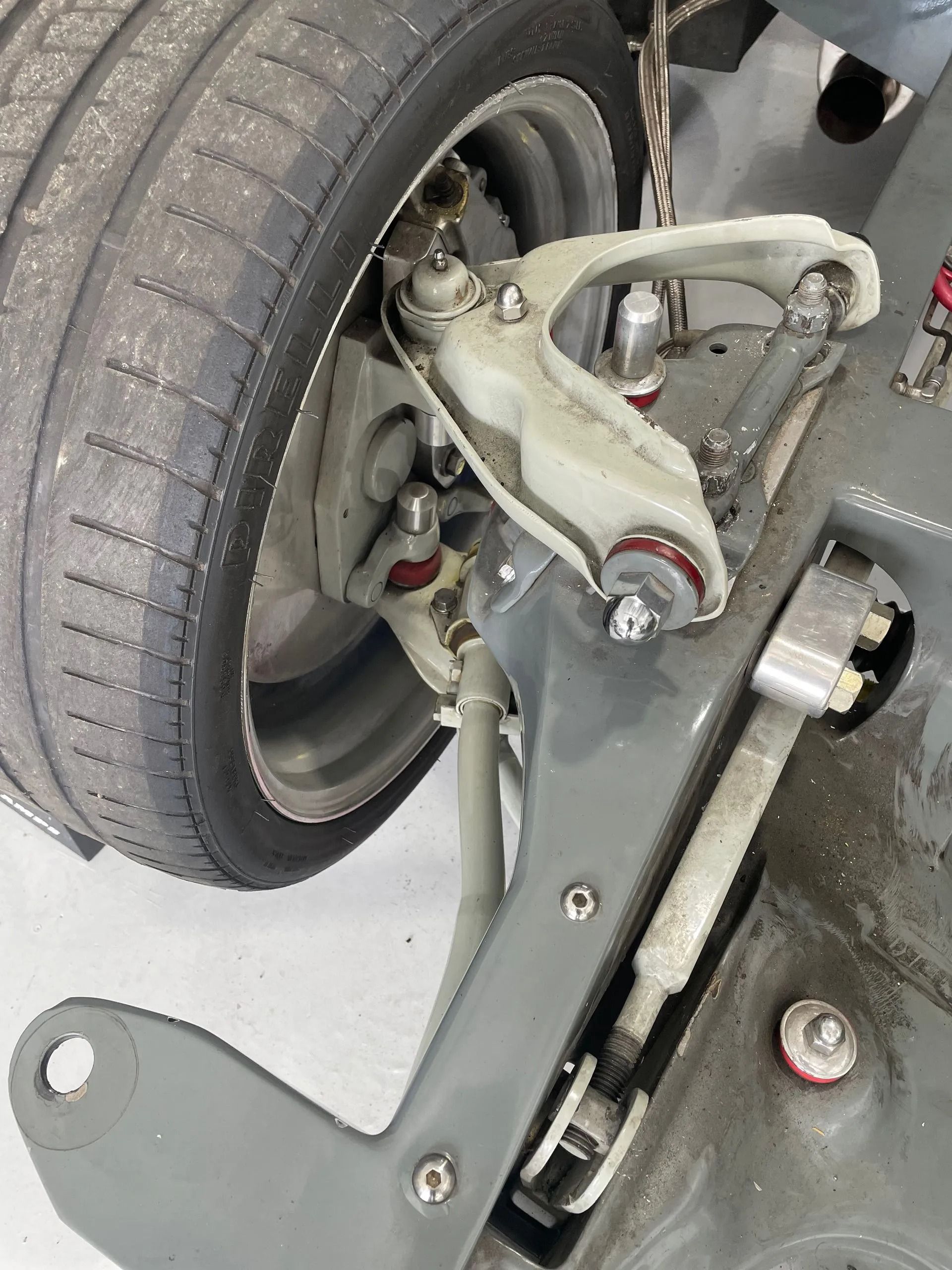 Close-up of a car wheel and exposed suspension/brake assembly in a garage.