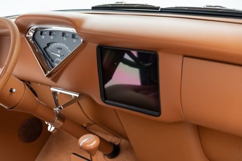 Classic car dashboard with tan leather trim, chrome accents, and a small встроенный screen display.