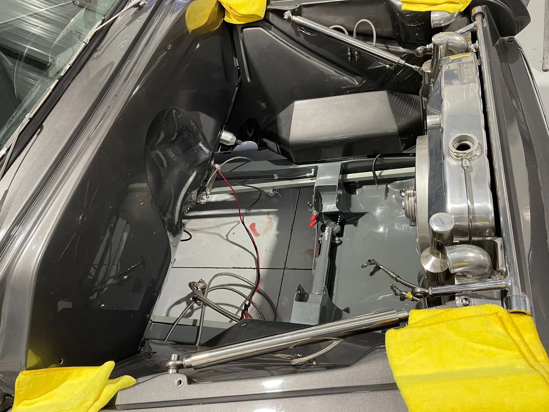 Interior of a mechanical compartment with wiring, metal parts, and yellow tape around the edges