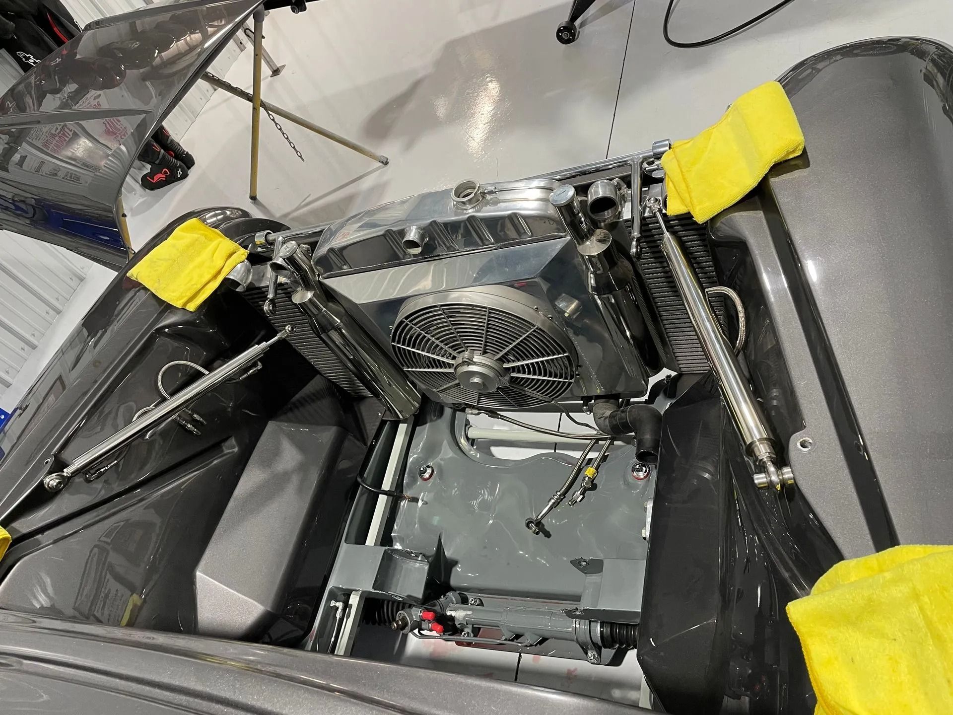 Car engine bay with a large cooling fan, silver components, and yellow protective covers on the fenders